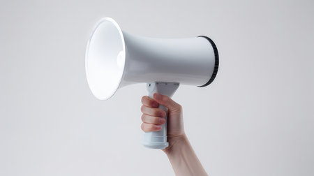 Female hand holding a megaphone isolated on a white background.の素材