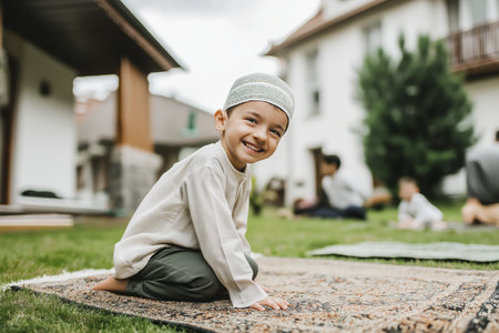 Smiling child in traditional clothing praying outdoors on a sunny day.の素材
