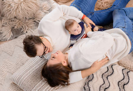 Young family dad moms and son lie on the carpet on the background of the New Year treeの写真素材