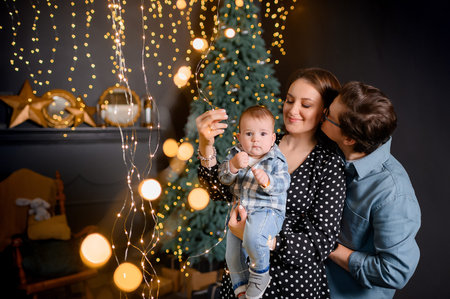Young family dad mom son toddler on Christmas tree decor background