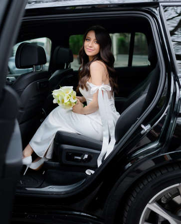 Beautiful bride with black hair gets out of the carの写真素材