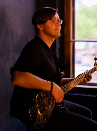 Handsome young guy playing bass guitar