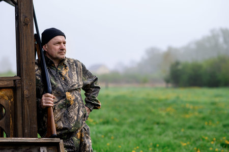 Man hunter with a gun leaned on a wooden wall