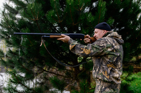Hunter aims a rifle against the backdrop of a misty lake