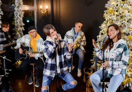 Young rock band sings and plays on the background of the Christmas tree