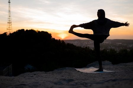 Silhouette of a beautiful young girl in a hijab meditates and practices yoga