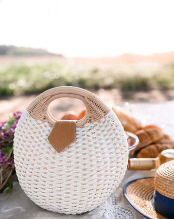 Summer straw handbag on a picnic on a background of sunsetの写真素材