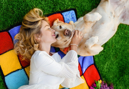 Beautiful caucasian blonde girl lying with a white Labrador dog in the garden