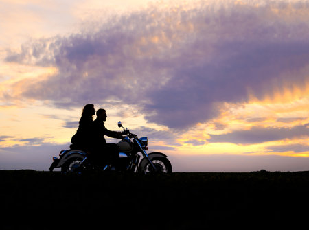 Silhouette of a couple riding a motorcycleの写真素材