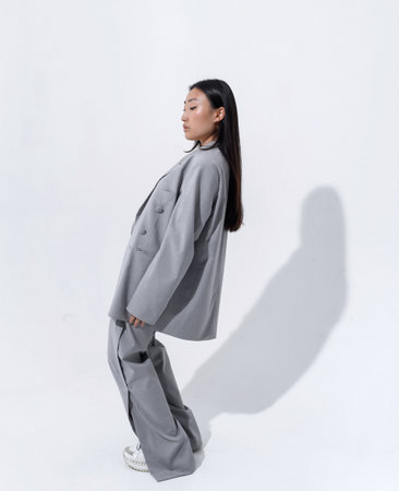 A beautiful Asian girl in a gray suit on a naked body posesの写真素材