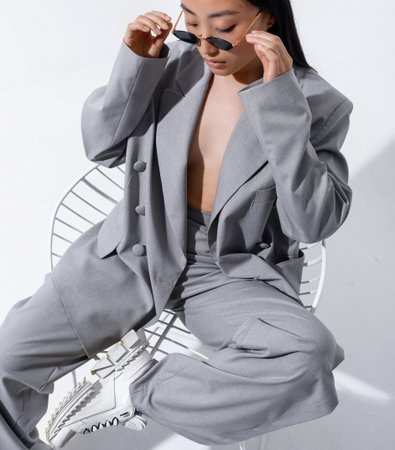 A beautiful Asian girl in a gray suit on a naked body poses