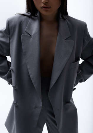A beautiful Asian girl in a gray suit on a naked body posesの写真素材