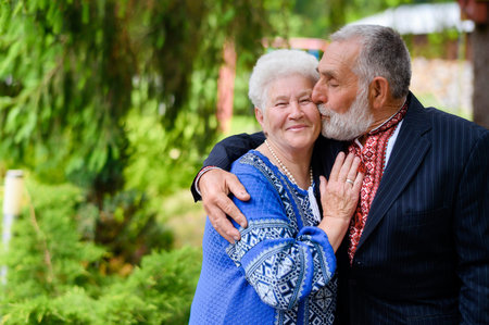 An old gray-haired woman hugs an old gray-haired man and sweetly kisses