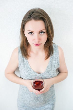 young beautiful girl with a glass of wine at homeの写真素材