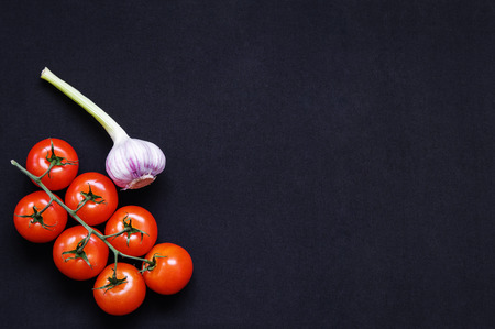 Food frame. Pasta ingredients. Cherry-tomatoes, spaghetti pasta, garlic, basil, parmesan and spices on dark grunge backdrop, copy space, top view, horizontal orientedの写真素材