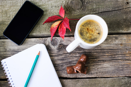 smartphone, a notebook for writing, a book and a cup of coffee, frame composition on vintage board backgroundの写真素材