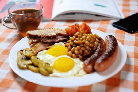 Traditional English or Irish breakfast: sausages, bacon, egg, mushrooms, tomatoes and toasts. Nutritious morning meal. horizontalの写真素材