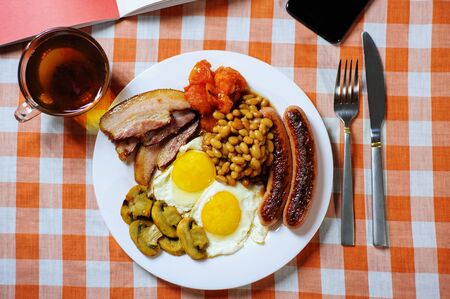Traditional English or Irish breakfast: sausages, bacon, egg, mushrooms, tomatoes and toasts. Nutritious morning meal. horizontalの写真素材