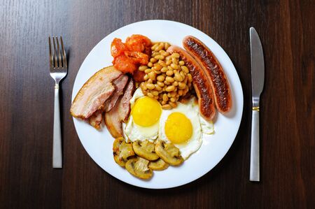 Traditional English or Irish breakfast: sausages, bacon, egg, mushrooms, tomatoes and toasts. Nutritious morning meal. horizontalの写真素材