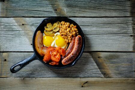 full irish breakfast with fried egg, sausages, black pudding, white pudding, baked beans, bacon, tomato and grilled mushrooms in a cast iron panの写真素材