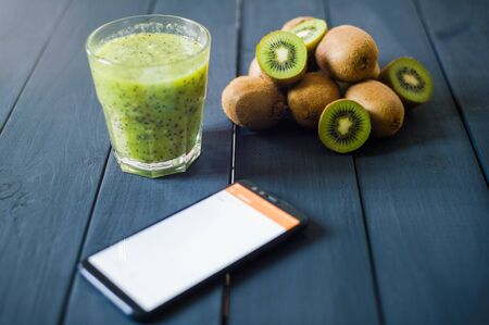 glass of kiwi juice with fresh fruits on black wooden tableの写真素材