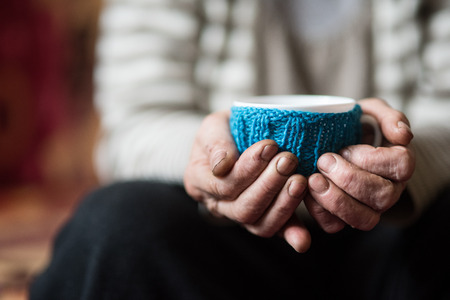 Elderly woman holding cup of hot coffee or teaの写真素材