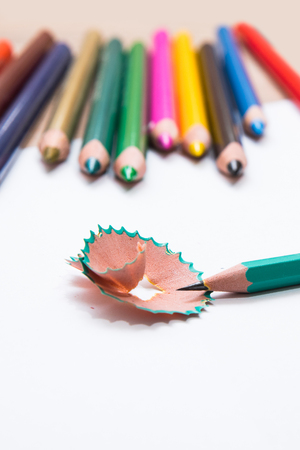 Green pencil and peelings with colorfuk crayons isolated on whiteの写真素材