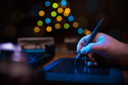 Graphic designer holding a pen over tablet.の写真素材