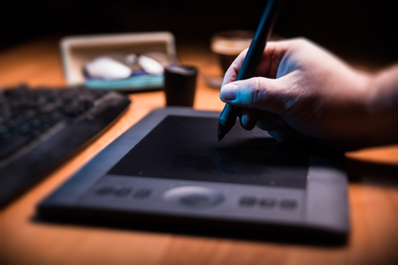 Graphic designer holding a pen over tablet.の写真素材
