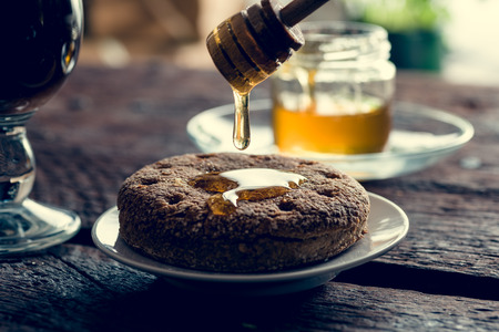 Oatmeal cookies on the wite plate on the wooden table with honeyの写真素材