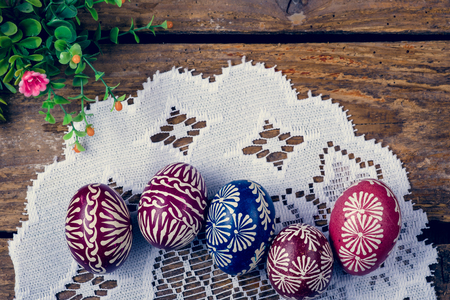 Hand-painted easter eggs, colorised, on the wooden table and embroidered napkinの写真素材