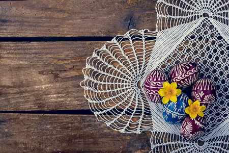 Hand-painted easter eggs, colorised, on the wooden table and embroidered napkin