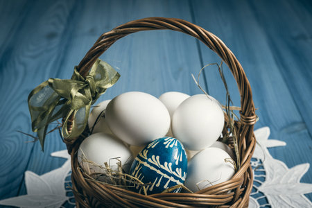 Group of eggs in the basket on the blue wooden surface. Easter concept.