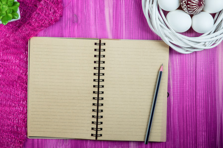 Flat lay view of painted and white easter eggs. Notepad ready to write wishesの写真素材