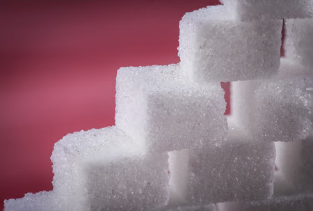The wall built of sugar cubes on the red wooden table