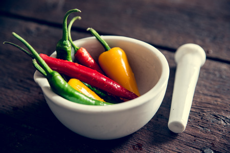 A group of colorful chili peppers in mortarの写真素材
