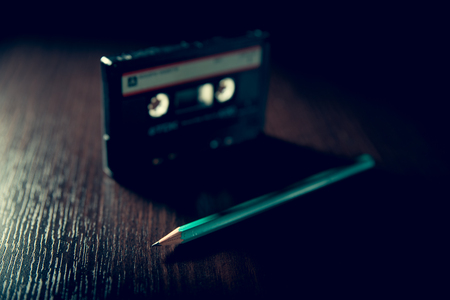 Old-fashioned cassette tape on the dark surface and green pencilの写真素材
