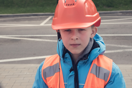 10 years old caucasian boy in safety helmet and reflective vest. Young engineer concept.の写真素材