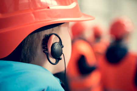 A boy in safety helmet with earphone in his ear. Young engineer concept.の写真素材