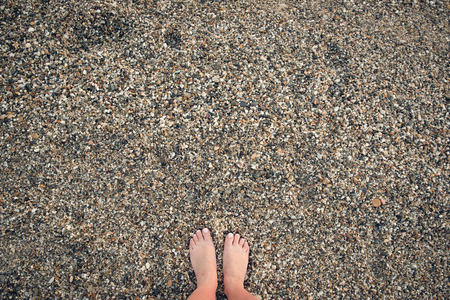 Woman's feet on the stony beach with big copyspaceの写真素材