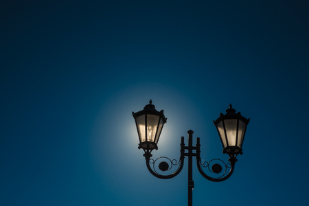 Two backlit street lamps witn blue sky in background in Tykocin. Polandの写真素材