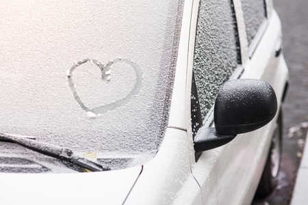 Shape of heart drawn on snow on front window of the car. First snow concept.の写真素材