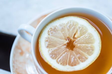 crockery cup of fresh prepared black tea with slice of lemonの写真素材