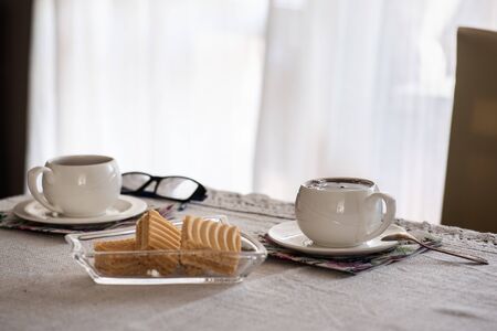Two white oldfashioned cup of tea or caffee on the table at home. Stay at home concept.の写真素材