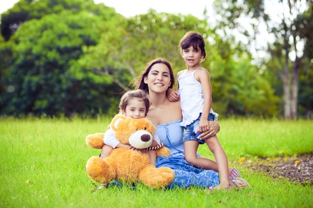 Young mother and two daughters playing in grassの写真素材
