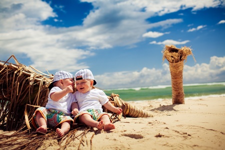 identical twin boys relaxing on tropical beachの写真素材
