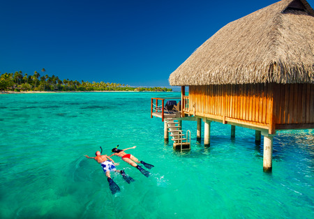 Young couple snorkling from hut over blue tropical lagoonの写真素材