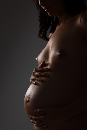 Profile of a nude young female pregnant bodyの写真素材