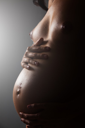 Profile of a nude young female pregnant body with jeweleryの写真素材