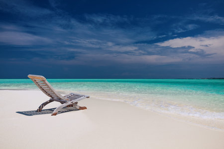 Beach view of amazing water in Maldives - empty chair on sand